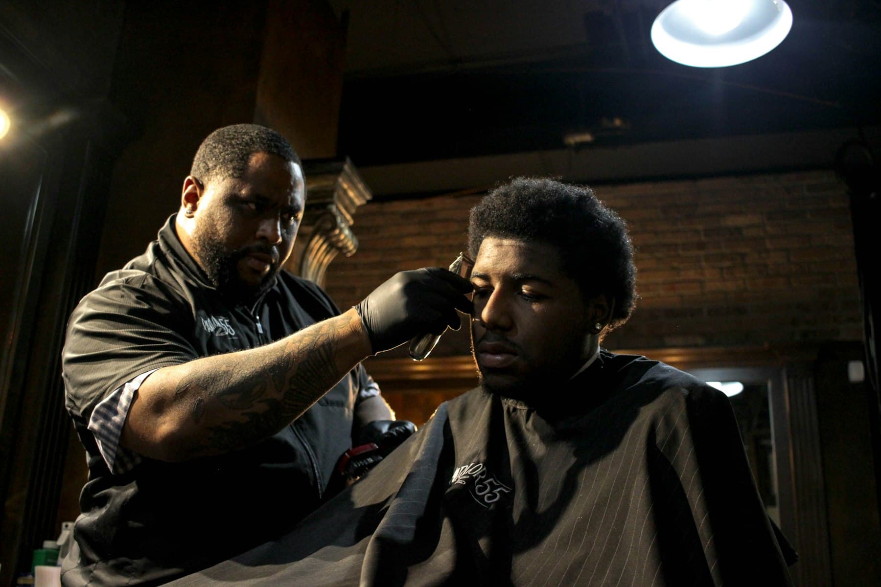 A barber trimming a client's hair with clippers.